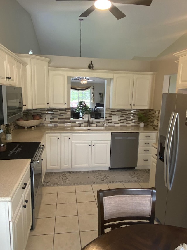 kitchen featuring sink, vaulted ceiling, light tile patterned flooring, white cabinetry, and stainless steel appliances