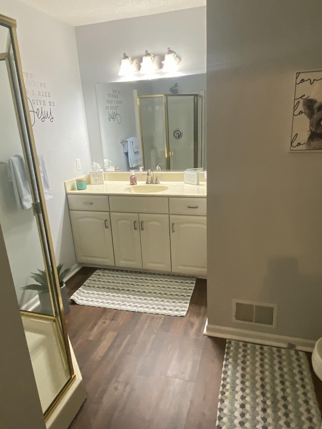 bathroom with hardwood / wood-style floors, vanity, and a shower with shower door