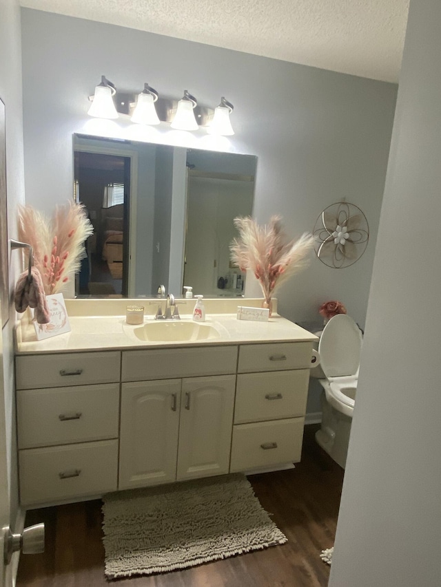 bathroom featuring a textured ceiling, vanity, hardwood / wood-style flooring, and toilet