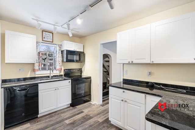 kitchen with hardwood / wood-style floors, track lighting, black appliances, sink, and white cabinetry