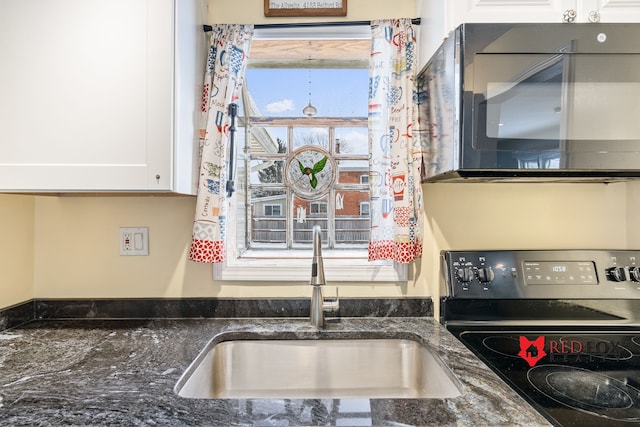 kitchen with white cabinets, dark stone countertops, sink, and range with electric cooktop