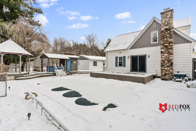 snow covered back of property featuring a gazebo and an outdoor structure