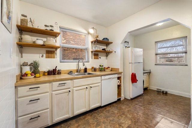 kitchen with butcher block countertops, backsplash, white appliances, and sink