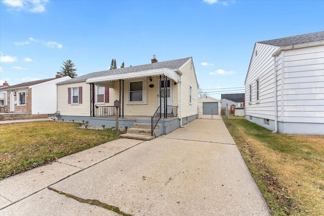 bungalow with an outbuilding, covered porch, a front yard, and a garage