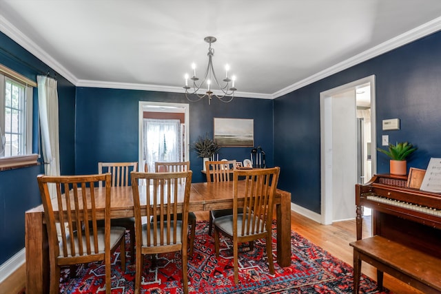 dining space featuring crown molding, a chandelier, and light wood-type flooring