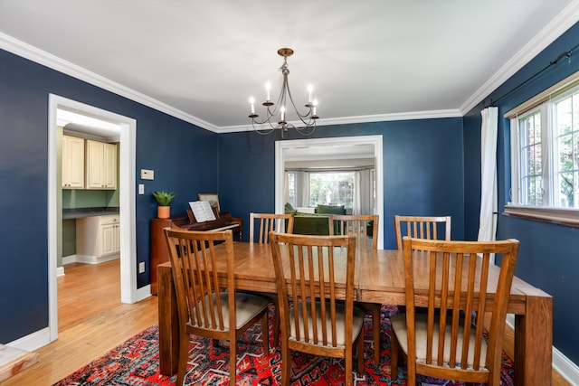 dining area with light hardwood / wood-style floors, a chandelier, and ornamental molding