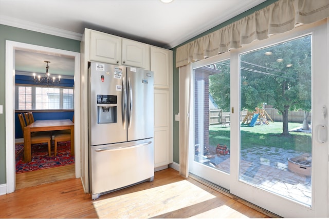 kitchen with stainless steel fridge, a wealth of natural light, a notable chandelier, white cabinets, and light hardwood / wood-style floors