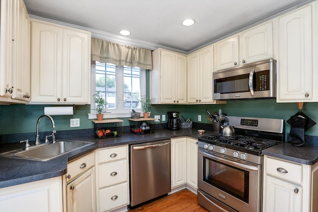 kitchen with hardwood / wood-style floors, sink, stainless steel appliances, and ornamental molding