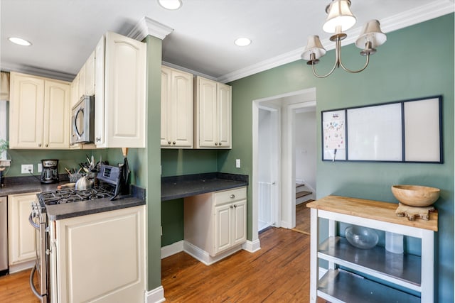 kitchen featuring hardwood / wood-style flooring, ornamental molding, appliances with stainless steel finishes, and an inviting chandelier