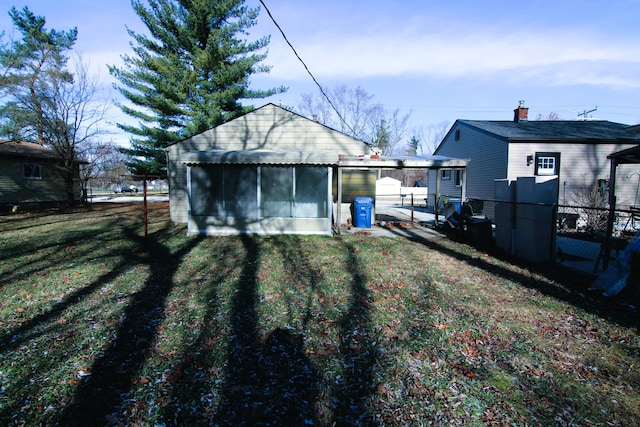 rear view of house featuring a lawn and a sunroom