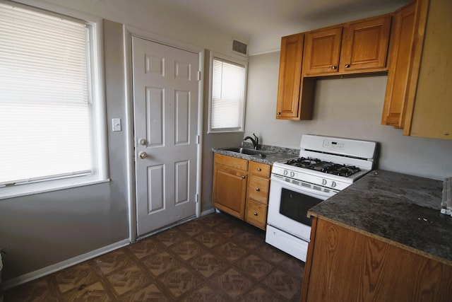 kitchen with gas range gas stove, sink, and dark stone counters