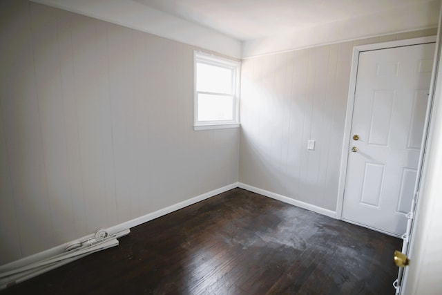 empty room with wood walls and dark hardwood / wood-style flooring