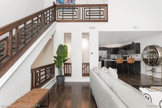 living room featuring a high ceiling and dark wood-type flooring