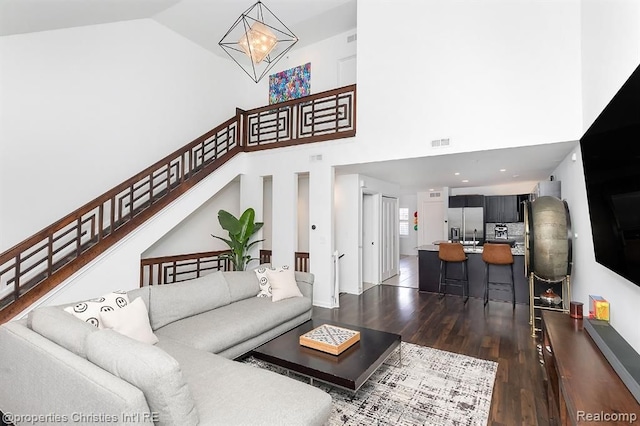 living room featuring high vaulted ceiling, an inviting chandelier, and dark wood-type flooring