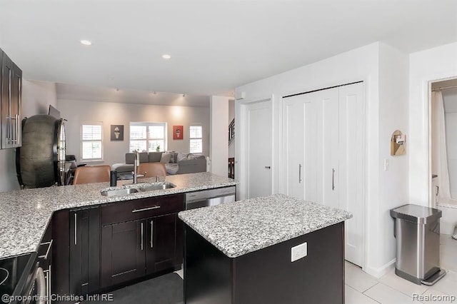 kitchen with dishwasher, sink, light stone counters, light tile patterned flooring, and a kitchen island