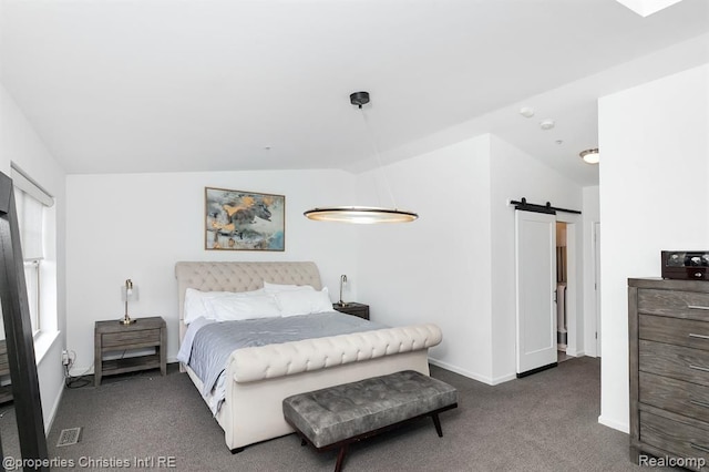 bedroom with a barn door, dark carpet, and lofted ceiling