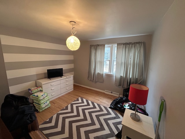 interior space with a baseboard heating unit, light wood-style flooring, and baseboards