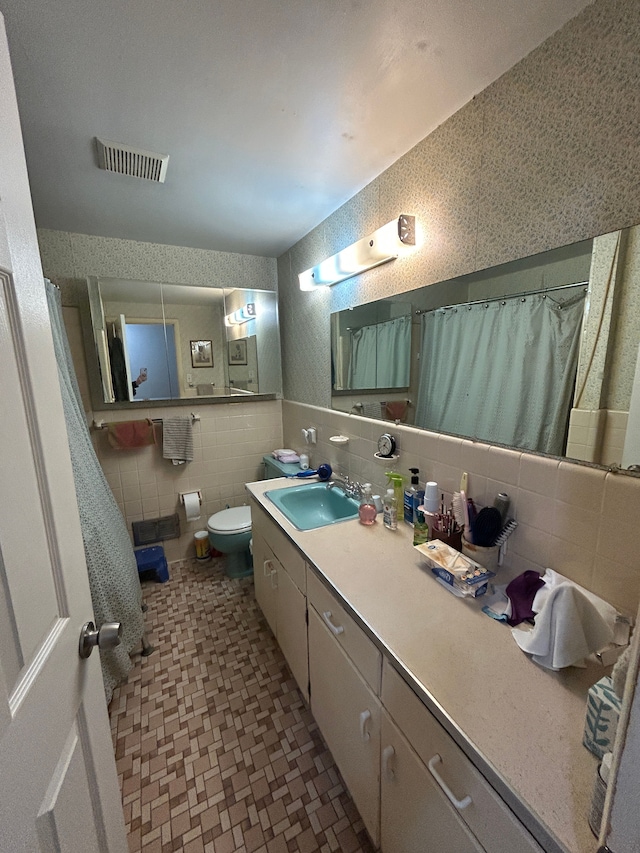 full bathroom with visible vents, toilet, curtained shower, vanity, and tile walls