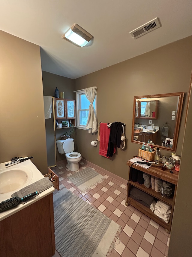 bathroom featuring toilet, vanity, visible vents, and baseboards