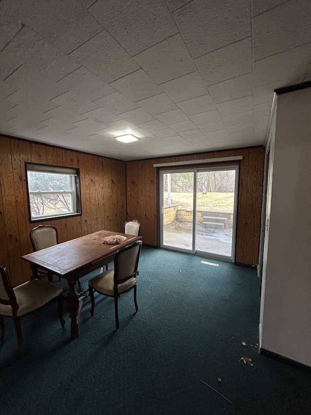 carpeted dining room with a wealth of natural light and wooden walls