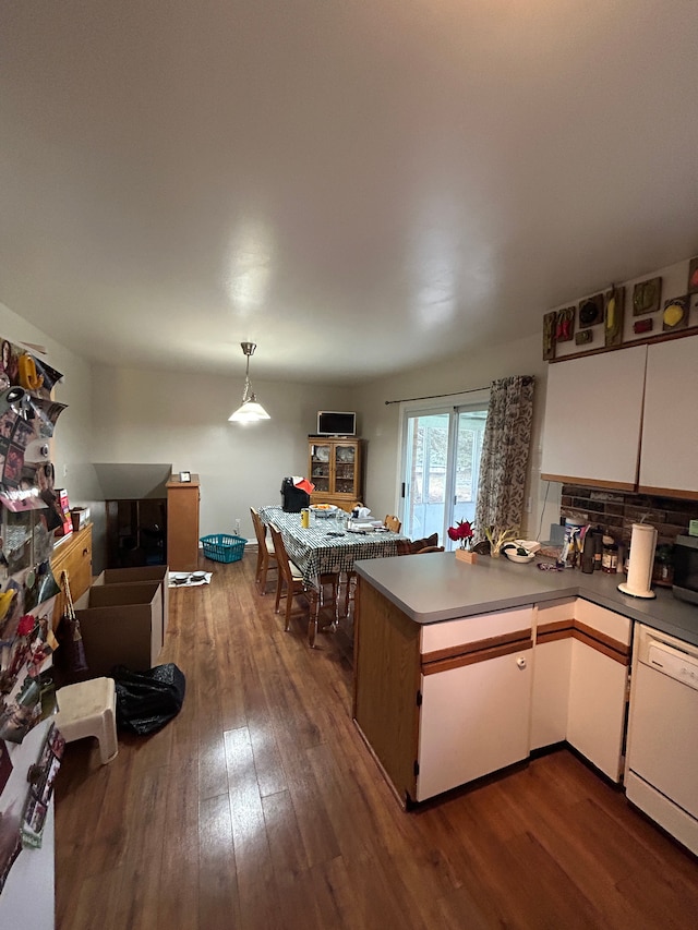 kitchen with dark wood-style flooring, tasteful backsplash, white cabinetry, white dishwasher, and a peninsula