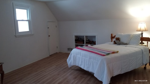 bedroom with visible vents, lofted ceiling, and wood finished floors