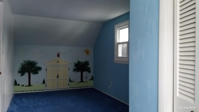 bonus room with dark colored carpet and lofted ceiling