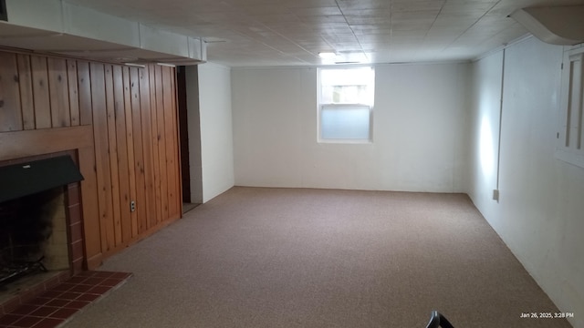 basement featuring a fireplace, wood walls, and carpet