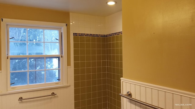 bathroom featuring radiator heating unit, a wainscoted wall, and tiled shower