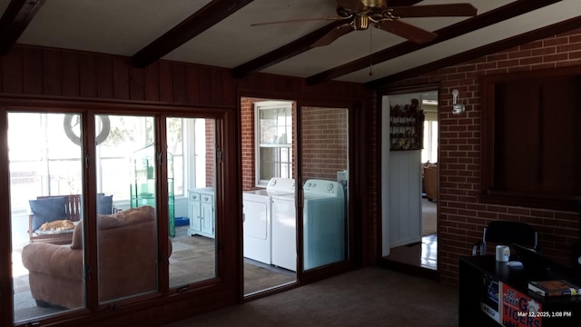 interior space featuring a ceiling fan, washer and dryer, brick wall, carpet flooring, and vaulted ceiling with beams