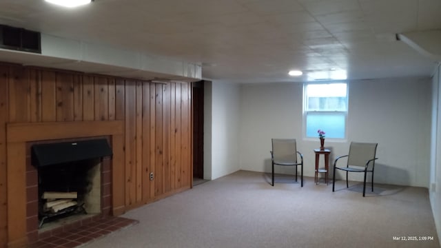 sitting room featuring carpet, a fireplace with raised hearth, visible vents, and wood walls