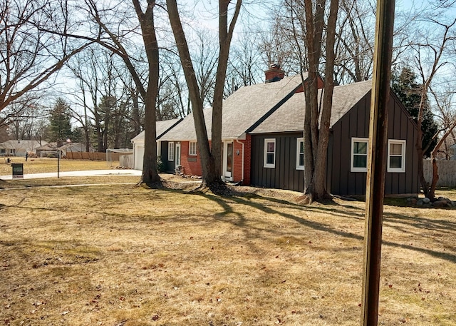 view of side of property with a garage, brick siding, board and batten siding, and fence