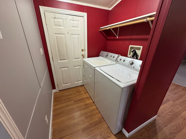 clothes washing area featuring independent washer and dryer, ornamental molding, and hardwood / wood-style floors