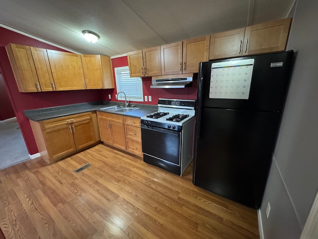 kitchen with vaulted ceiling, range with gas cooktop, sink, light hardwood / wood-style floors, and black fridge