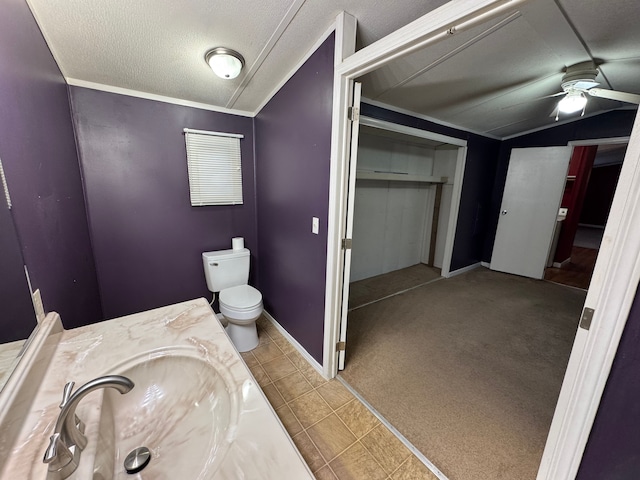 bathroom with lofted ceiling, ceiling fan, vanity, a textured ceiling, and toilet