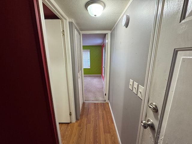 hall featuring light hardwood / wood-style floors and a textured ceiling