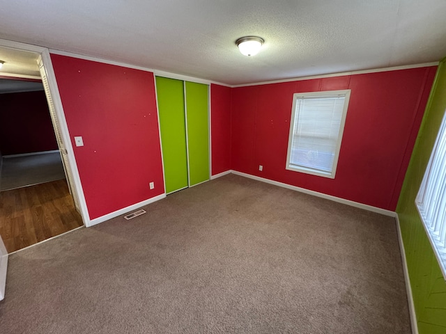 unfurnished room with carpet and a textured ceiling