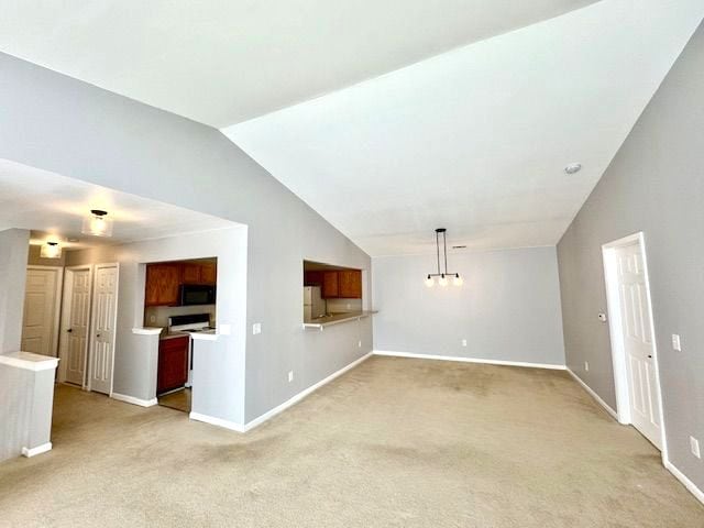 unfurnished living room with light colored carpet and vaulted ceiling