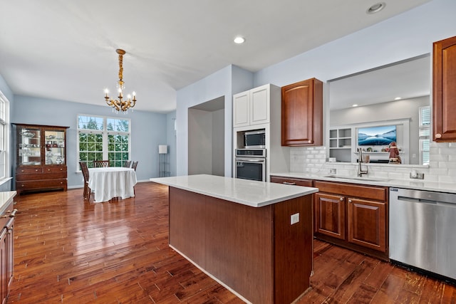 kitchen featuring sink, stainless steel appliances, tasteful backsplash, a notable chandelier, and a kitchen island