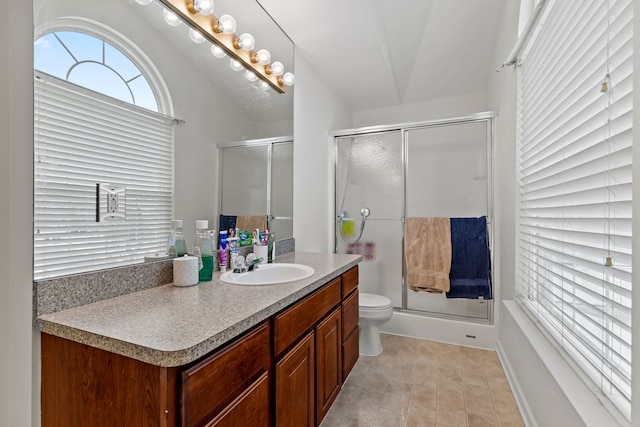 bathroom featuring tile patterned floors, vanity, a shower with shower door, and toilet