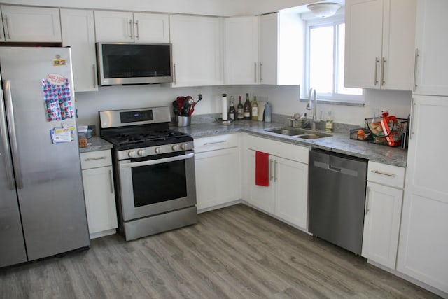 kitchen with white cabinetry, appliances with stainless steel finishes, sink, and light hardwood / wood-style flooring