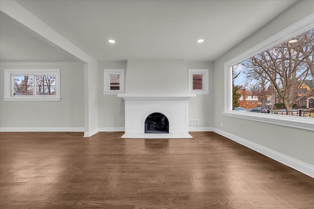 unfurnished living room with a brick fireplace and dark wood-type flooring