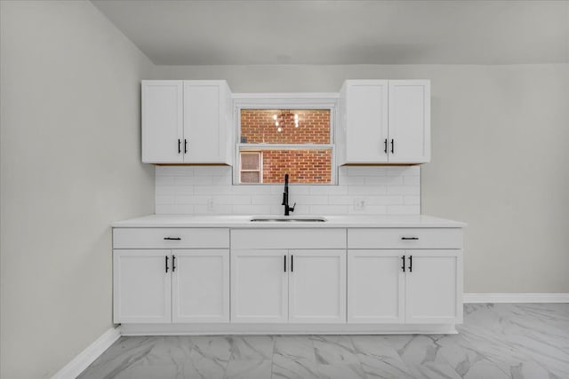 kitchen featuring decorative backsplash, white cabinetry, and sink