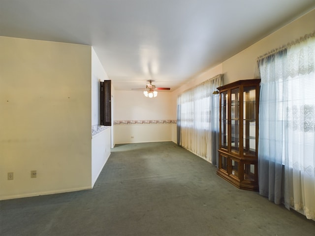 unfurnished room featuring dark colored carpet and ceiling fan