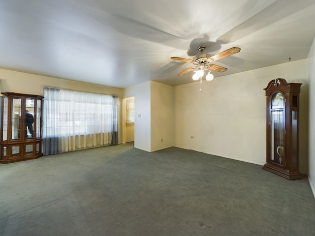 unfurnished living room featuring a wealth of natural light, ceiling fan, and dark colored carpet