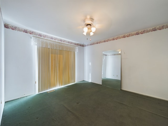 spare room featuring dark colored carpet and ceiling fan