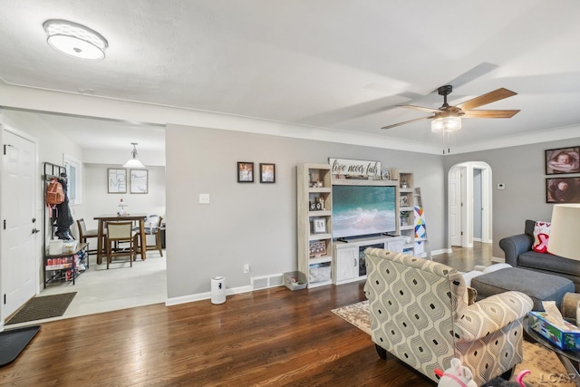 living area featuring a ceiling fan, visible vents, arched walkways, dark wood finished floors, and baseboards