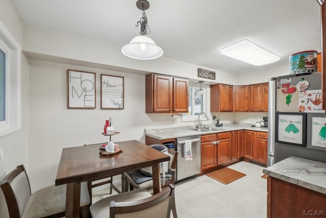 kitchen with brown cabinetry, decorative light fixtures, a sink, light countertops, and stainless steel appliances