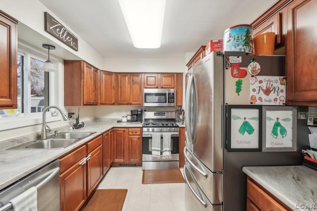 kitchen featuring light countertops, brown cabinets, a sink, appliances with stainless steel finishes, and decorative light fixtures