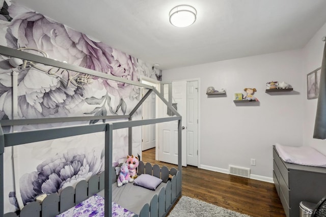 bedroom with visible vents, baseboards, and wood finished floors